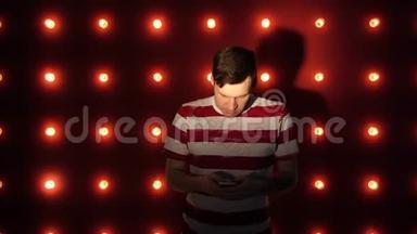 快乐的年轻人用智能手机站在明亮的墙边。 概念：<strong>喜讯</strong>或好消息